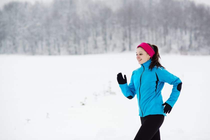 Young woman runs through the snow