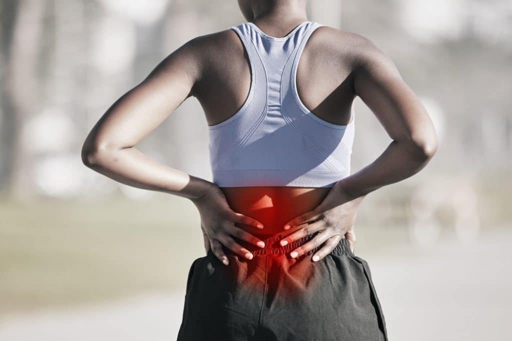 A woman suffers from back pain while working out