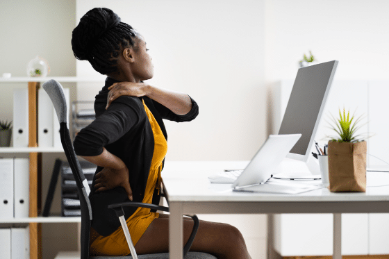 A woman struggles with her back pain at work and attempts to adjust her posture